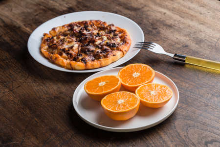 Delicious italian pizzas served on wooden table wiht orangeの写真素材