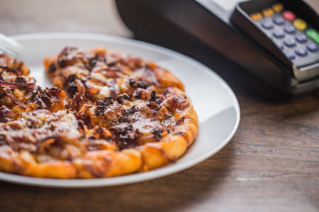 Delicious italian pizzas served on wooden table with payment terminalの写真素材