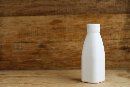 white plastic milk bottles on retro wooden table backgroundの写真素材