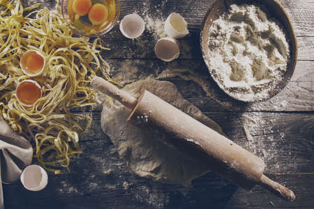 Process of cooking pasta with raw fresh ingredients for classic italian food - raw eggs, flour on...