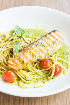 Spaghetti pesto salmon in white plate on wooden tableの写真素材