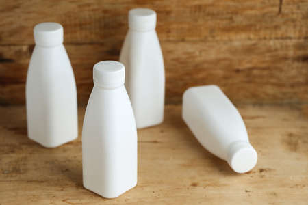 white plastic milk bottles on retro wooden table background