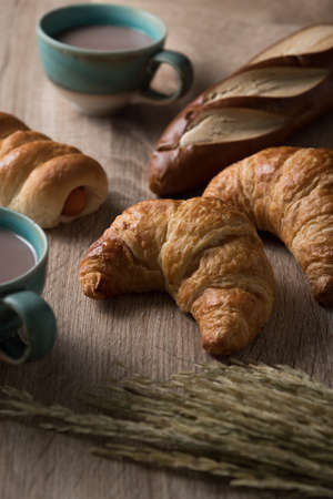 Croissants with bread and coffee cup on wooden backgroundの写真素材