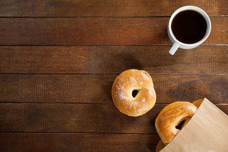 Cup of coffee with bun on wooden tableの写真素材