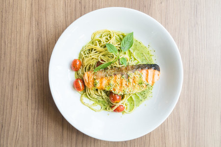 Spaghetti pesto salmon in white plate on wooden tableの写真素材