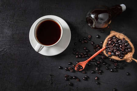 .Hot coffee and raw coffee beans on a black background.