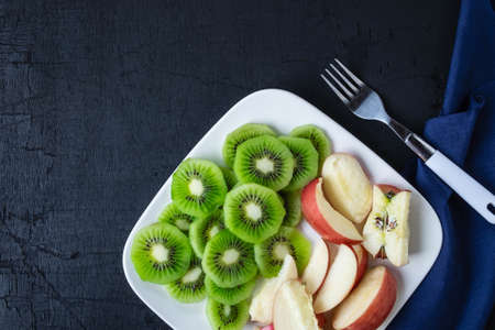 Mixed Fruit fresh kiwi and apples with grapes in a plate on a wooden table.の写真素材
