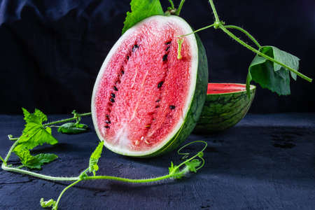 Fresh Water melon fruit cut in half on a black background.