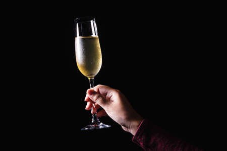 Woman hand holding glasses of champagne on the black background