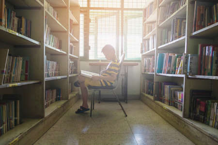 A boy reading a book in the libraryの写真素材