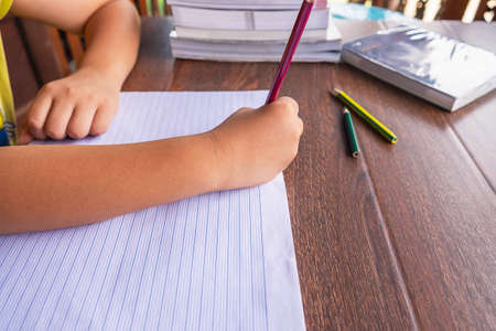 The students hand is written on paper on the school table.の写真素材