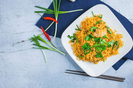 Stir noodles with vegetables in a white plate on a wooden floor.の写真素材