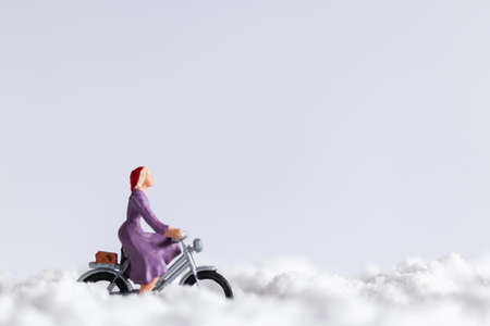Miniature people : Travelers riding a bicycle on snow backgroundの写真素材