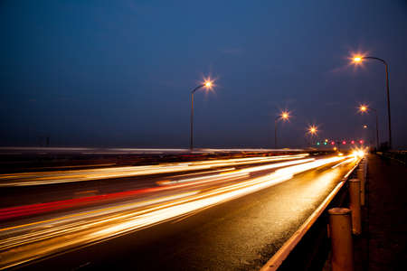 Street at night with cars running back and forth on the bridge.