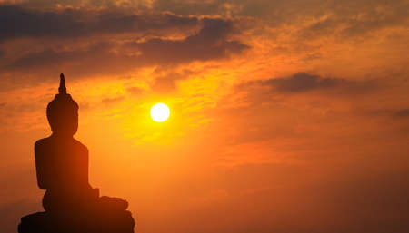 Silhouette Buddha on a sunset background shining from behindの写真素材