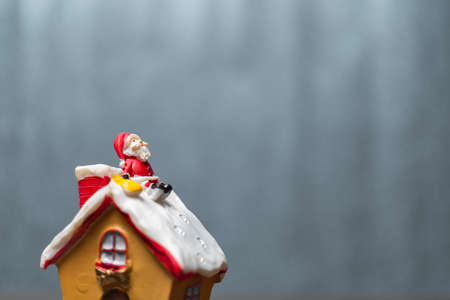 Merry Christmas and happy holidays! Cute Santa Claus sitting on the roofの写真素材