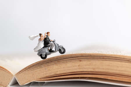 Miniature people : Couple riding the motorcycle on old bookの写真素材