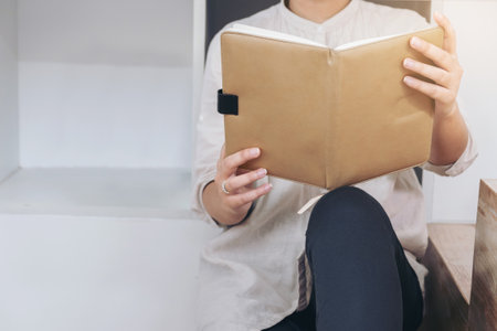 Young hipster woman teenager relaxing sitting in living room reading a books, Vacation and Education...