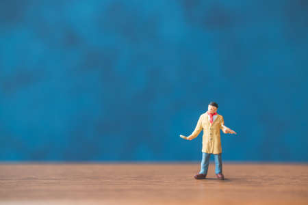 Miniature people holding brush in front of a blue wall backgroundの写真素材