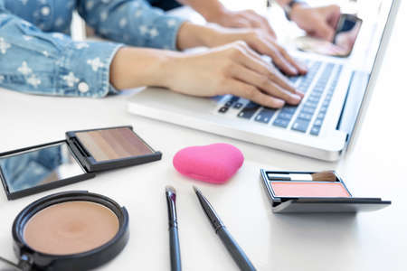 Makeup and beauty blog, elegant female fashion blogger working with a laptop, many cosmetics and...