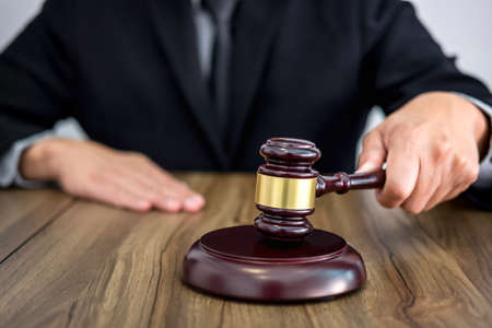 Male lawyer or judge hands striking the gavel on sounding block, working at courtroom, Law and justice conceptの写真素材