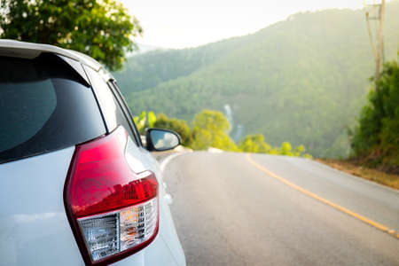 Close up of White car that is stained with mud after rain on mountain road and sunset, Travel and Relaxedの写真素材