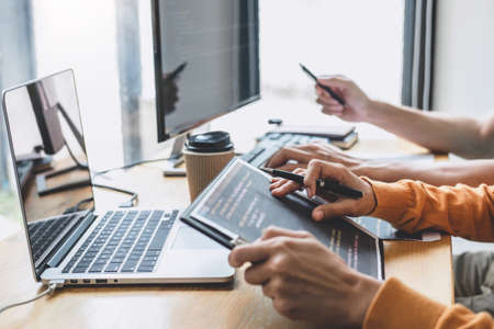 Writing codes and typing data code technology, Programmer cooperating working on web site project in a software developing on desktop computer at company, Programming with HTML, PHP and javascriptの写真素材