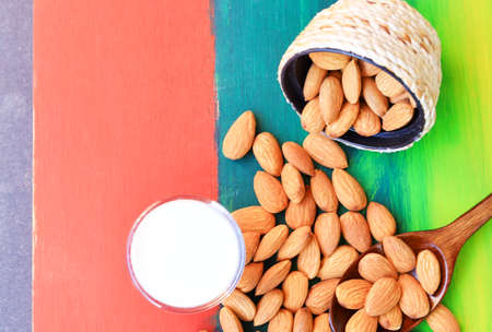 Almonds and milk in a glass on a beautiful colored natural wooden floor