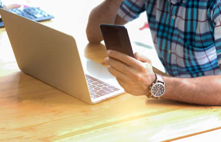 Young business people are using smartphones or mobile phones and laptops to work at home on holidays. Concepts of working and doing business onlineの写真素材