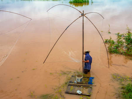 Fisherman in the Mekong with ancient fishing toolsの写真素材