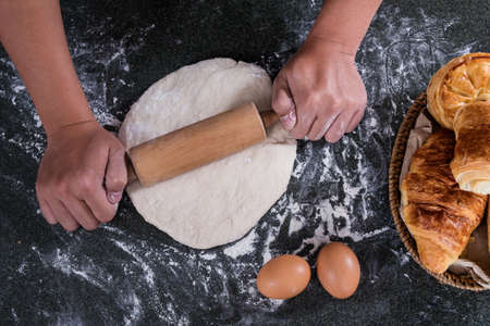 Male hands kneading dough sprinkled with flour table, Hands preparing bread, Raw dough for bread...