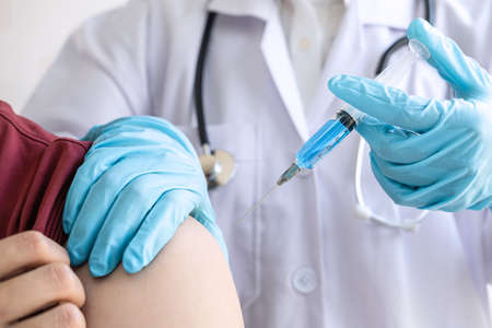 Doctor making injection vaccination patient to prevent pandemic of the disease, flu or influenza virus in clinicの写真素材