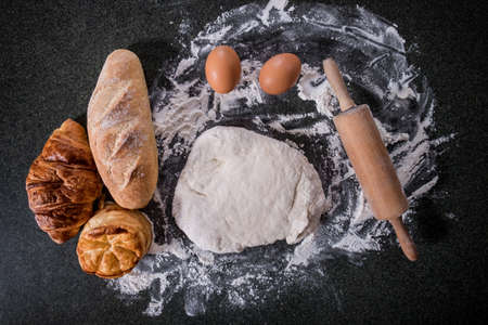 Raw dough for bread with ingredients on black background, top view