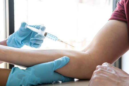 Doctor making injection vaccination patient to prevent pandemic of the disease, flu or influenza virus in clinicの写真素材
