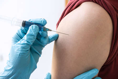 Doctor making injection vaccination patient to prevent pandemic of the disease, flu or influenza virus in clinicの写真素材