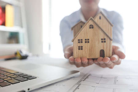 architect holding model of house wood to present and give to customer, real estate conceptの写真素材