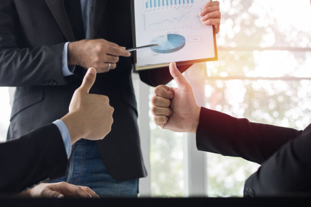 Businessman talking with colleagues show thumb about finance and success of company as presentation , conceptt as teamwork and team of business.の写真素材