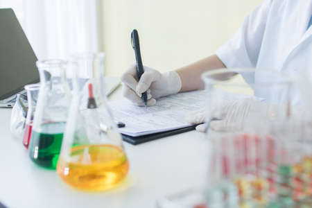 researcher or scientist writing information result and note on paper in science labの写真素材