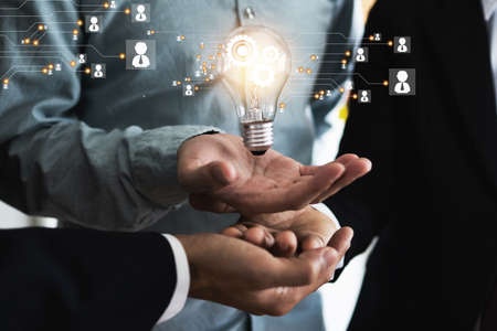 Innovation and idea of professional leader with teamwork holding lighting bulb with business icon and technology line, brainstorming teamwork and thinking management conceptの写真素材