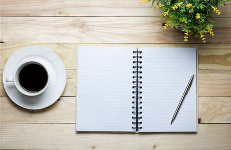 notebook pen and coffee on wood background with copy space