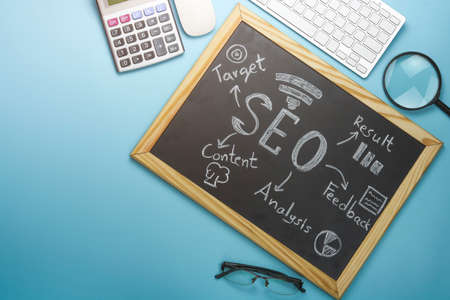 Top view of SEO Search Engine Optimization on black board and graph paper with magnifying glass,...