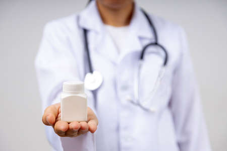 Close up hand of doctor show and holding bottle of pill, healthy and professional pharmacology help conceptの写真素材