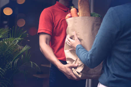 Delivery man send bag of vegetables and food to customersの写真素材