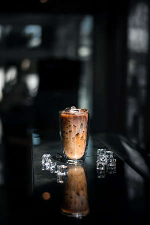 Close-up glass of iced coffee with milk on the tableの写真素材