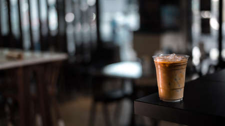Close-up plastic glass of iced coffee with milk on the table