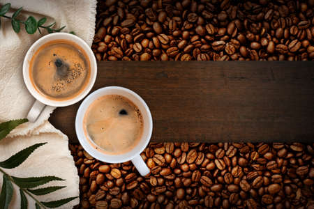 Cup of coffee with coffee beans on tableの写真素材
