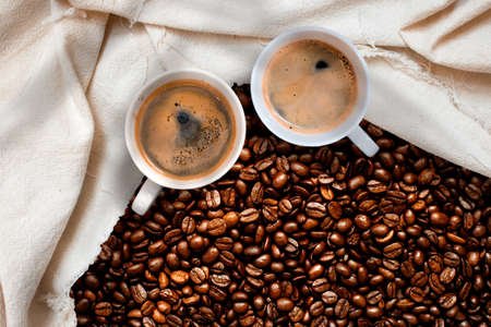Cup of coffee with coffee beans on table
