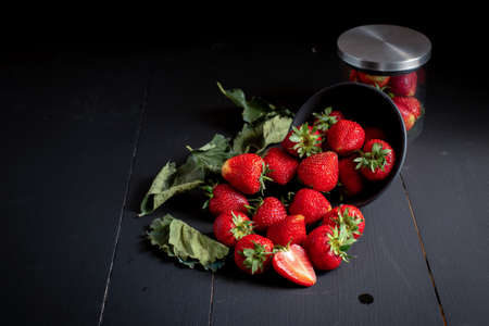 Ripe red strawberries on black wooden table