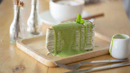 Green tea crepe cake with green tea leaf on wooden plate