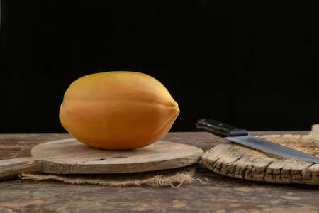 Ripe papaya fruit cut into pieces on wooden background